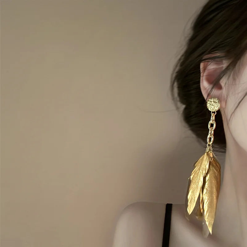 Aretes grandes con plumas doradas